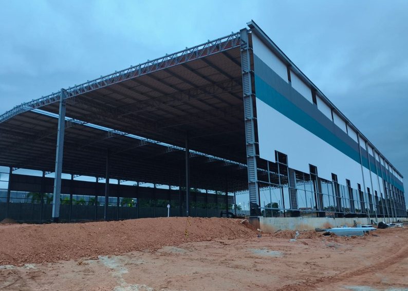 Galpão em construção com pilares, treliças e cobertura metálica